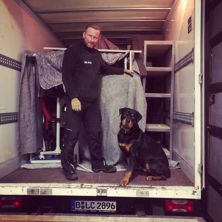EVIL OFFICE Mitarbeiter mit Hund im Firmenwagen beim Möbeltransport